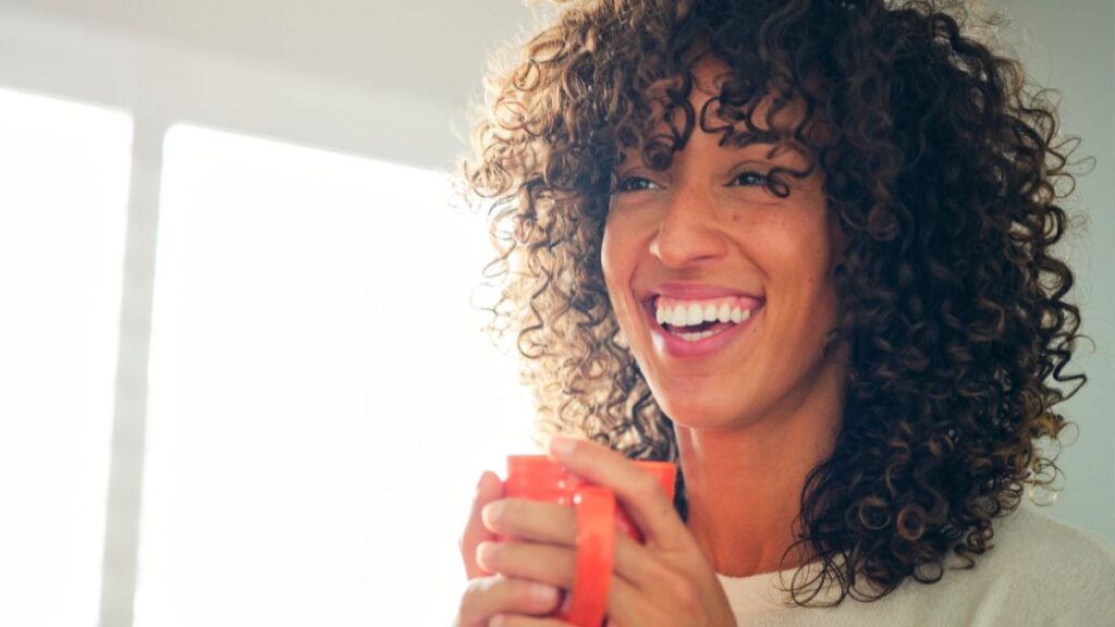 woman happy and smiling drinking coffee after overcoming fatigue after quitting alcohol