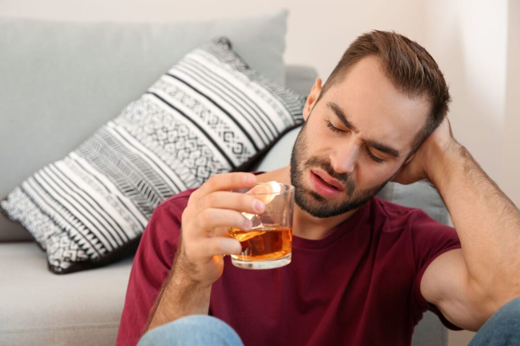 man sitting on the floor leaning against the couch discovering what are delirium tremens