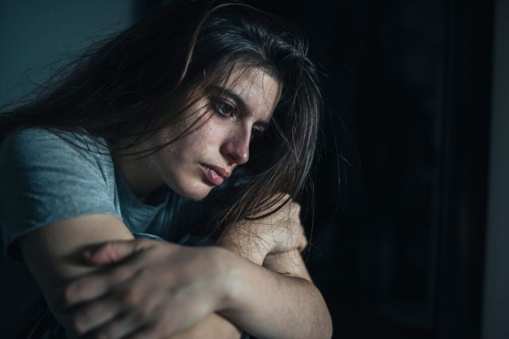 woman sitting in the dark struggling with using meth vs cocaine