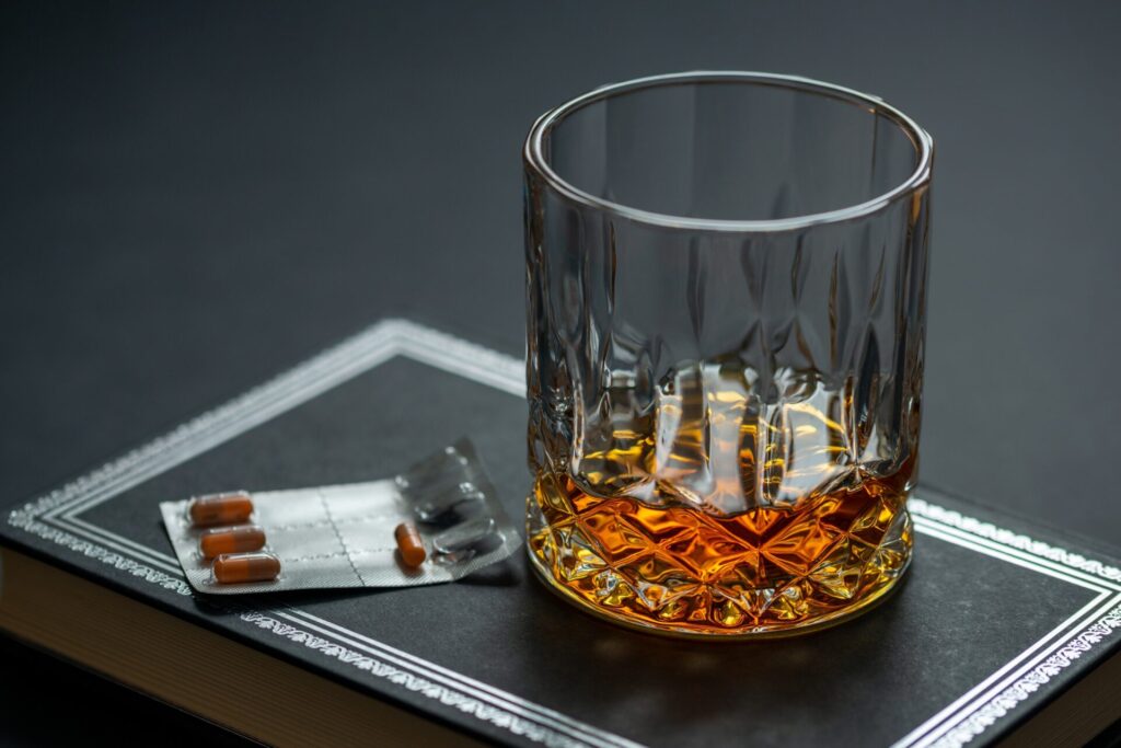 photo of a glass of alcohol and a sheet of pills like someone is mixing alcohol and medication