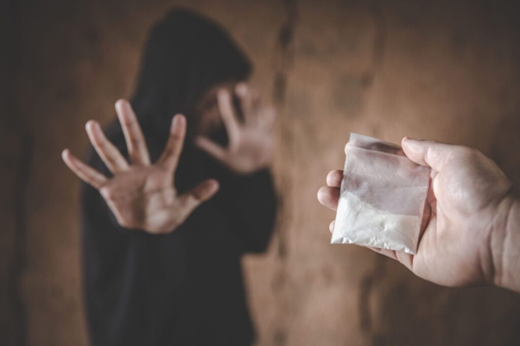 man holding his hand up turning down someone offering him pink cocaine