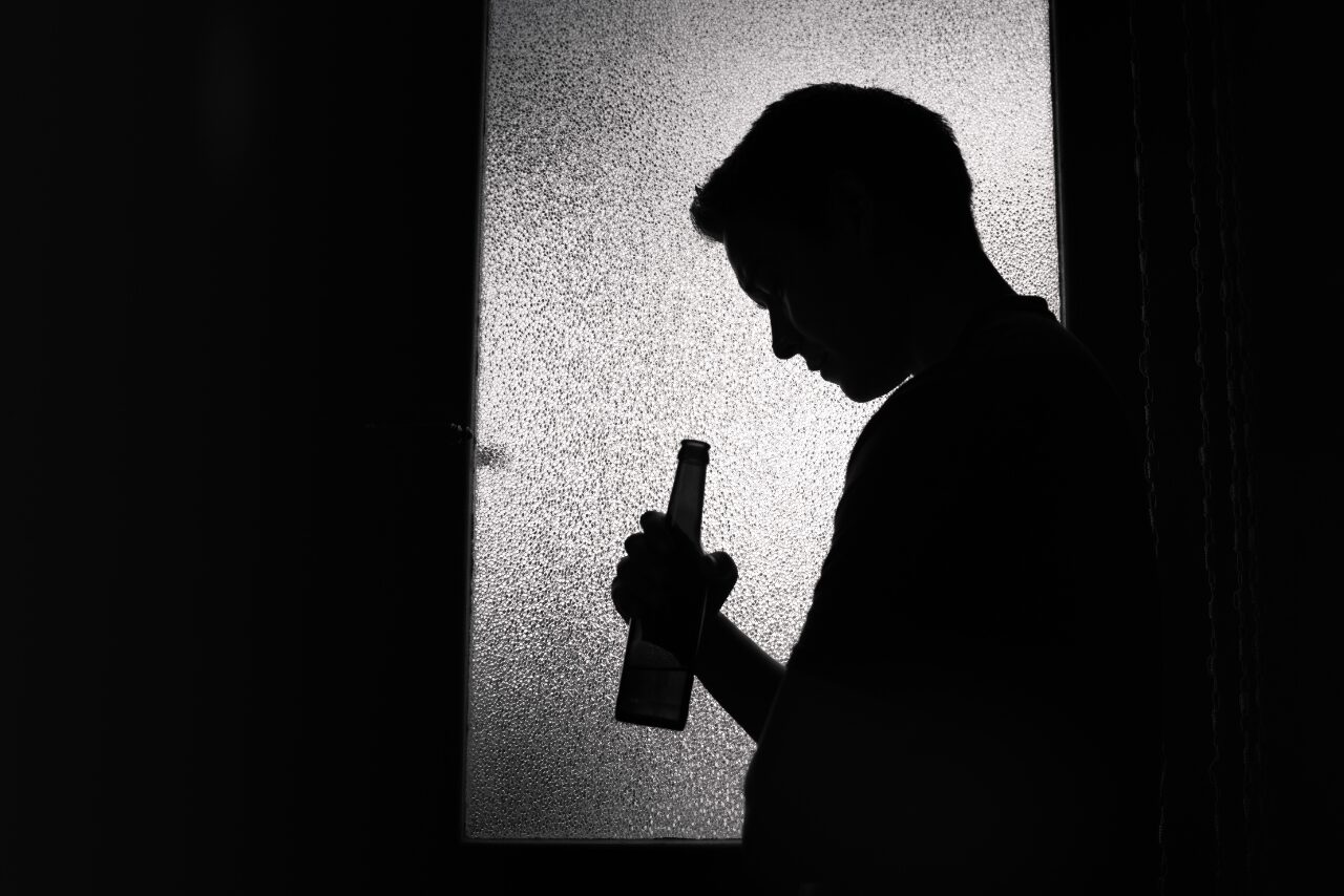 man standing in the dark wondering how long does it take to get addicted to alcohol