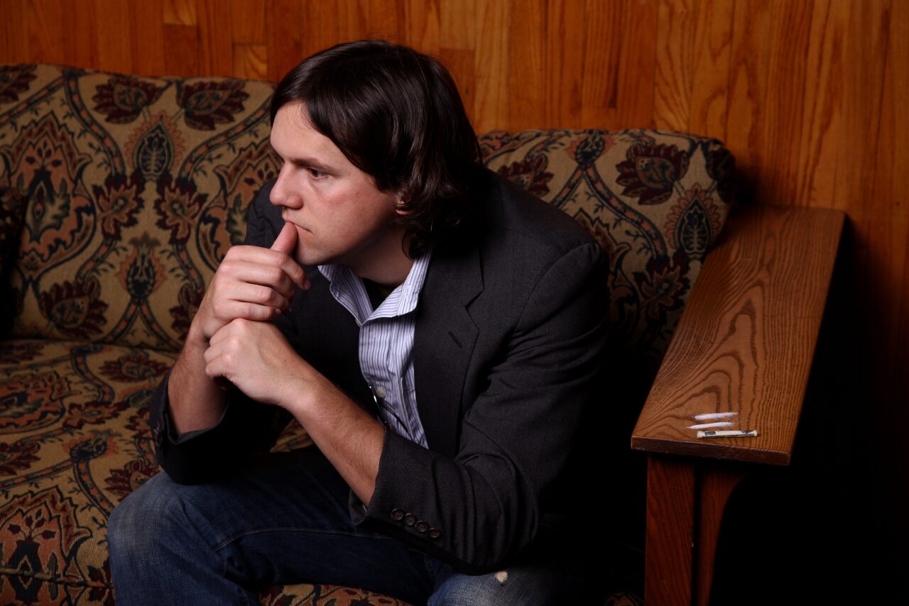 man sitting on the couch with lines of cocaine next to him pondering why is cocaine so addictive