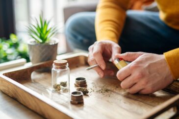 man sitting at a table smoking marijuana wondering are weed shakes dangerous?