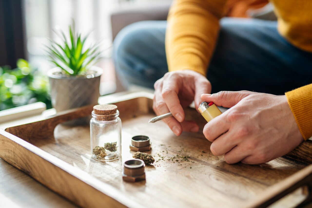 man sitting at a table smoking marijuana wondering are weed shakes dangerous?